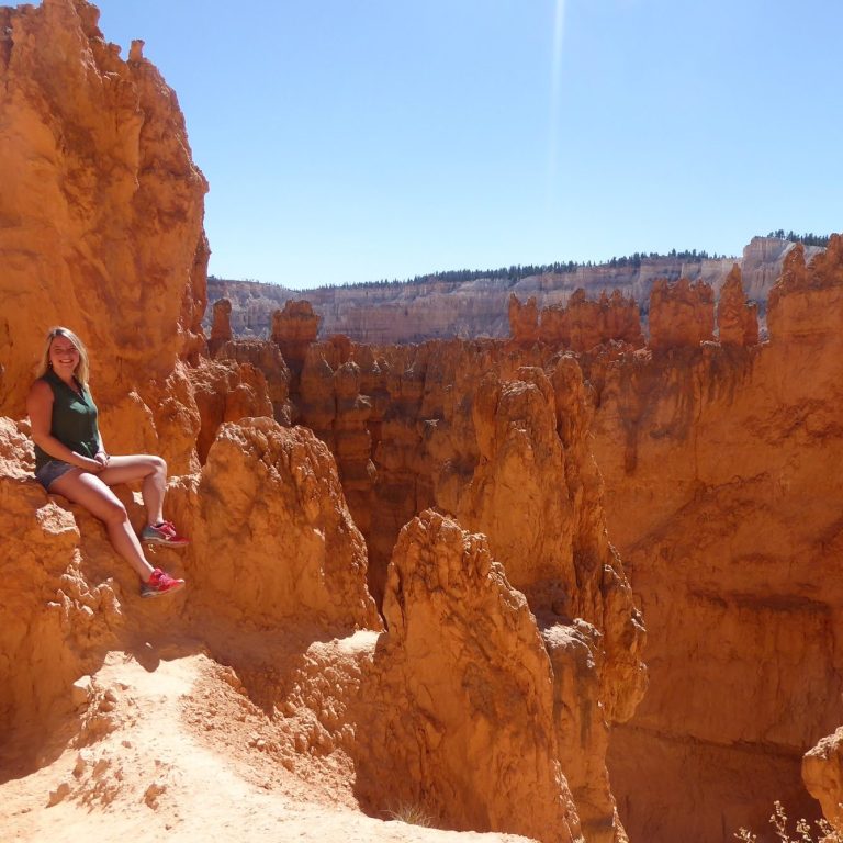 Bryce Canyon Vrouw zit op een rots in Bryce Canyon, omringd door oranje rotsformaties.